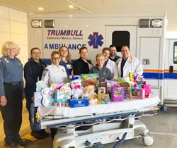 Emergency Medical services staff posing around a large collection of gifts