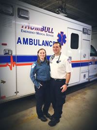 Emergency Medical Technicians pose in front of an ambulance